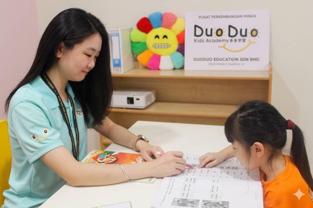 DuoDuo teacher guiding a girl through a worksheet at the centre
